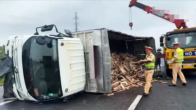 Xe tải chở gỗ lật ngang đường trên cao tốc